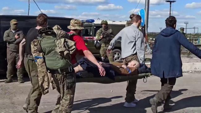 A Ukrainiansoldier is carried on a stretcher escorted by pro-Russian military personnel after leaving the besieged Azovstal steel plant. Picture: AFP.