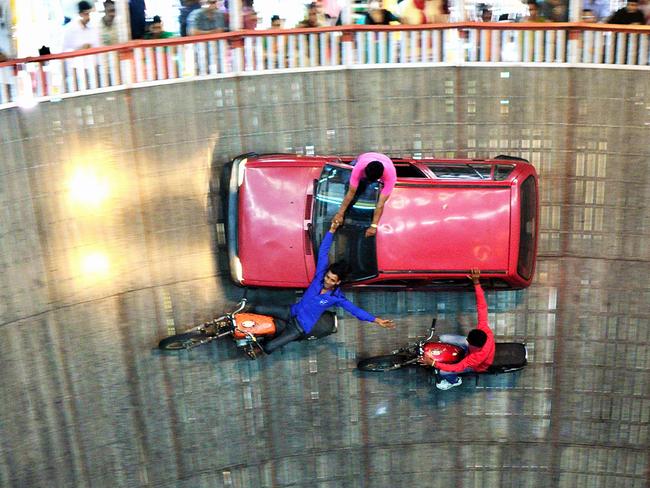 PIC BY SUBHENDU BAGCHI / CATERS NEWS - (PICTURED: WELL OF DEATH CAR AND MOTORCYCLE STUNTS) These stunning shots showcase one of the worlds most exciting motor stunts - known as the WELL OF DEATH. Motorcyclists and car drivers defy gravity as they drive around the wells seemingly vertical walls. The well - which ranges from six to 11 meters in diameter - originates from American motordome racing in the early 1900s but has become a popular carnival sideshow in India. Vehicles are not pinned to the wall, but held in place by centripetal force which allows objects to follow a curved path, similar to a loop-the-loop in a rollercoaster. - SEE CATERS COPY