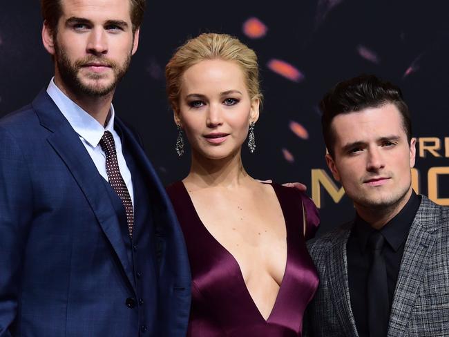 (From L) Australian actor Liam Hemsworth, US actress Jennifer Lawrence, and US actor Josh Hutcherson pose for photographers on the red carpet as they arrive for the world premiere of the movie "The Hunger Games: Mockingjay — Part 2", in Berlin on November 4, 2015. AFP PHOTO / JOHN MACDOUGALL