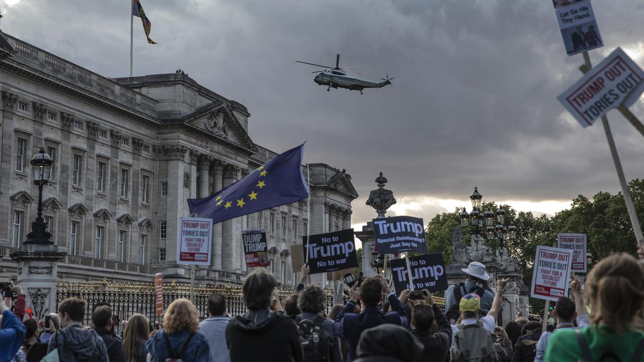 People hold placards in protest over Donald Trump's state visit outside Buckingham Palace.