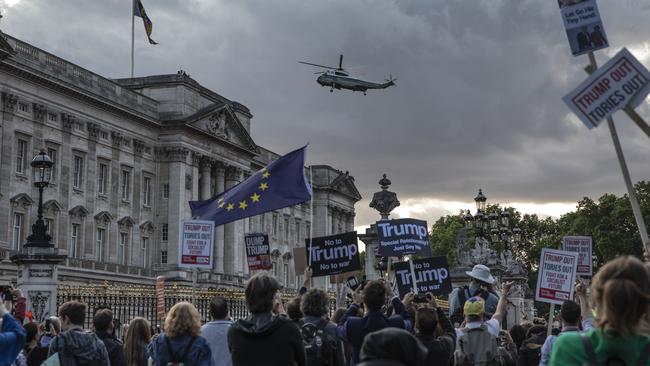 People hold placards in protest over Donald Trump's state visit outside Buckingham Palace.