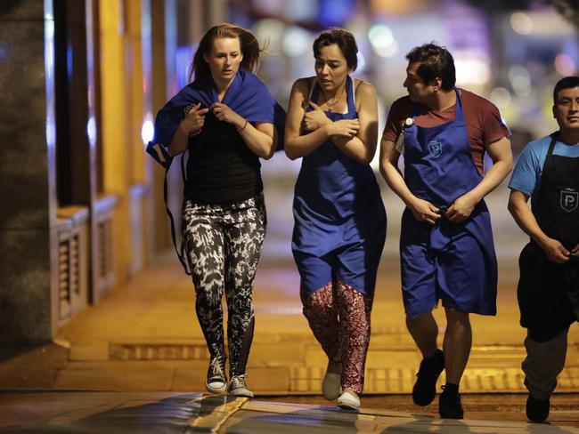 People walk away just before midnight from inside a police cordon after an attack in London. Picture: AP