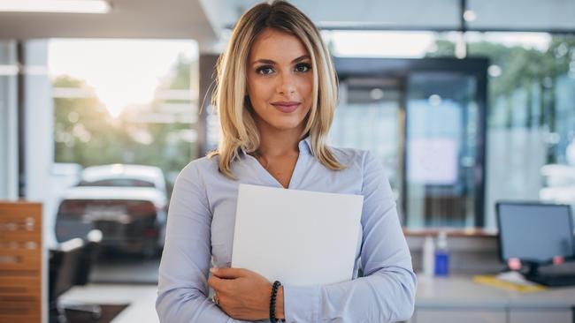 CAREERS: One woman, portrait of a young beautiful saleswoman at the car dealership store.