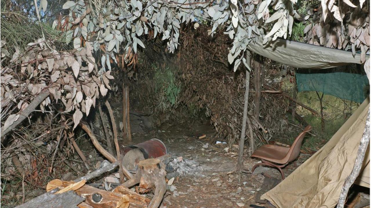Inside one of the Train’s sniper hides made of branches and leaves with a chair, a tarp covering and the remnants of a fire.