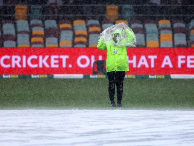 A member of security adjusts a rain cover as he stands near the covers as the rain teems down on day one. Picture: AFP