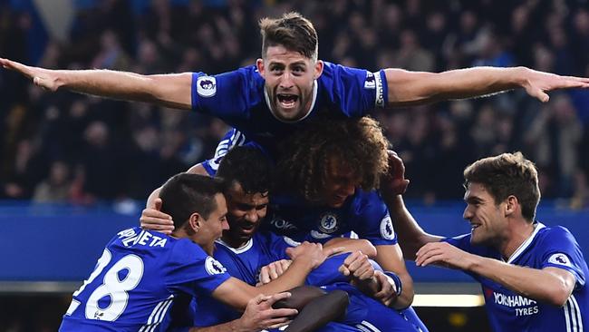 Chelsea's English defender Gary Cahill (top) jumps onto the huddle.