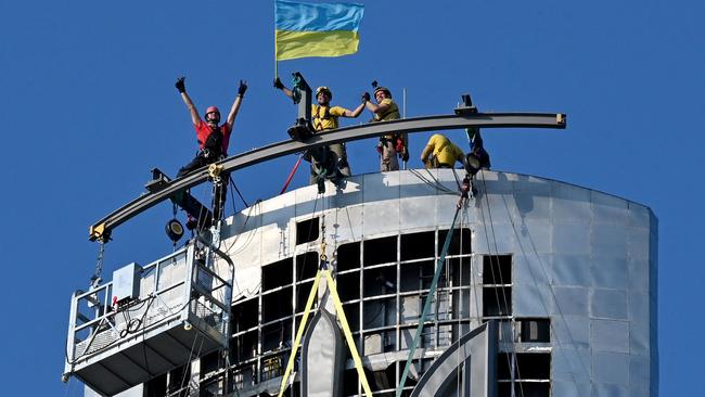 Steeplejacks install the Ukrainian coat of arms, also known as the tryzub, replacing those of the former Soviet Union on the Motherland Monument in Kyiv. Picture: AFP