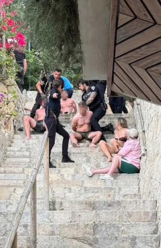 The 'drunk' Brits were seen cuffed on steps by the beach club. Picture: Solarpix