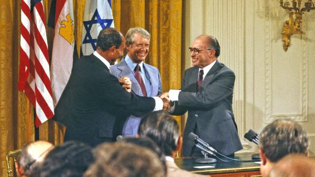 Egyptian president Anwar Sadat (left), Carter and Israeli prime minister Menachem Begin shake hands at the signing ceremony for the Camp David Accords in 1978.