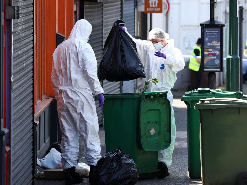 Police forensics officers search through bins outside a shop on Ilkeston Road in Nottingham, central England, following a 'major incident' in which three people were found dead. (Photo by Darren Staples / AFP)