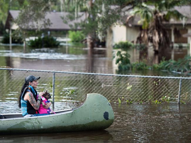 A woman and her dog navigate floodwaters caused by Hurricane Irma on September 12, 2017 in Middleburg, Florida, United States. The storm brought flooding to areas not seen in generations. Picture: AFP