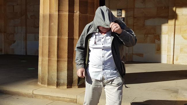 Driving instructor Kenneth Campbell covers his face outside the Adelaide Magistrates Court. Picture: Sean Fewster.