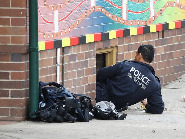 A police officer climbs under a classroom during the search. One man was arrested at Prestons Public School. Picture: David Swift