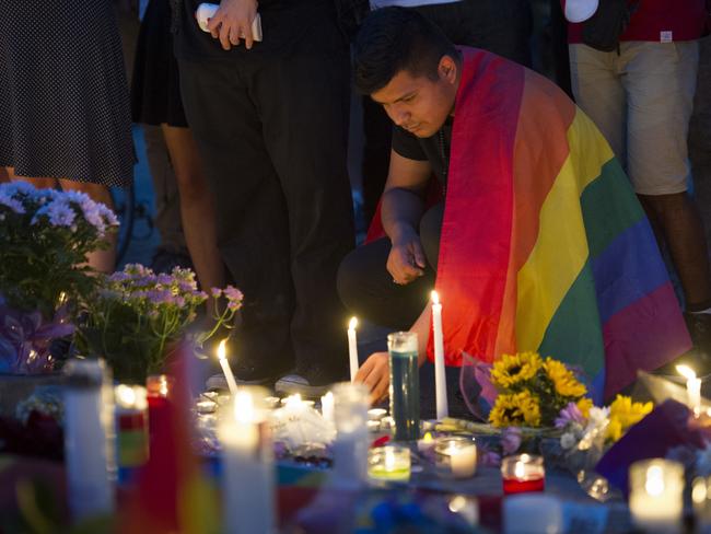 An unidentified man, wrapped in a Rainbow Flag, lights a candle during a vigil in Washington. Picture: AP