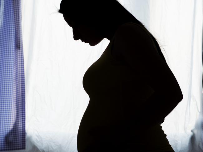 Silhouette of pregnant woman in her bedroom