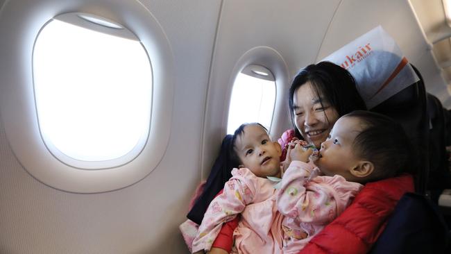 Mum Bhumchu holds Nima and Dawa during the flight from Bhutan to Bangkok. Picture: Alex Coppel