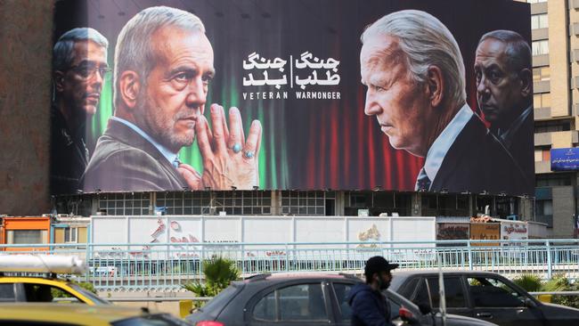 Commuters drive past a billboard bearing pictures of Iran's President Masoud Pezeshkian and Joe Biden. Picture: AFP.