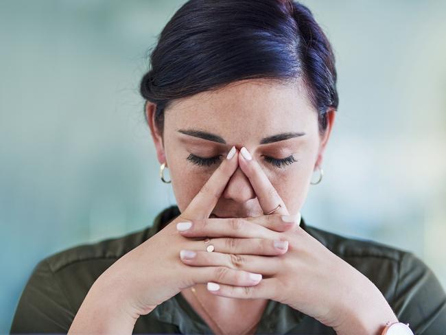 Shot of a young businesswoman looking stressed out while working in an office