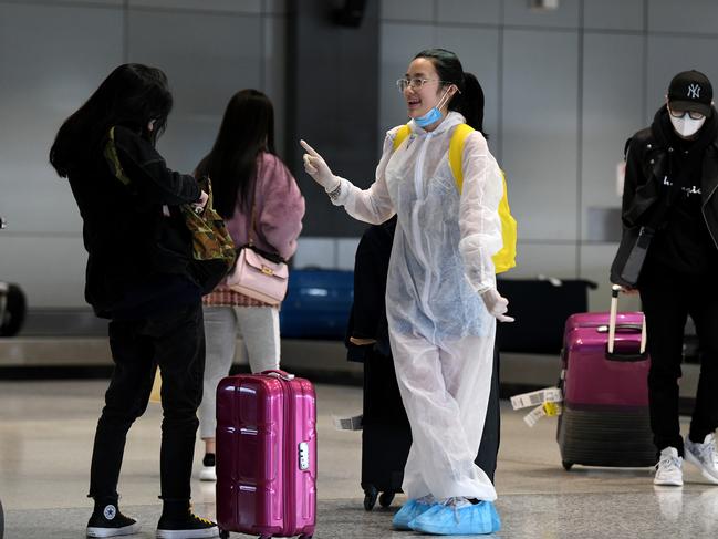 A passenger wearing a protective suit and mask is seen collecting baggage after arriving on a flight from Melbourne at Sydney Airport, Friday, July 3, 2020. Incoming passengers from Melbourne will face a security blitz at Sydney Airport after at least five travellers from Victoria's coronavirus hotspots were detected after flying in on Thursday. (AAP Image/Bianca De Marchi) NO ARCHIVING