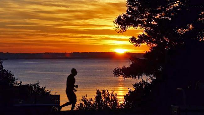 A lone jogger enjoys sunrise over Botany Bay from Brighton Le Sands this morning. Pic: John Appleyard