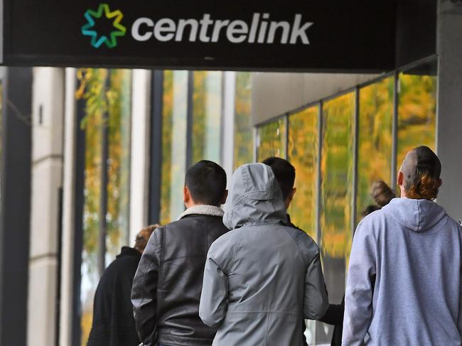 People queue up outside a Centrelink office in Melbourne on April 20, 2020, which delivers a range of government payments and services for retirees, the unemployed, families, carers and parents amongst others. - A report from the Grattan Institute predicts between 14 and 26 per cent of Australian workers could be out of work as a direct result of the coronavirus shutdown, and the crisis will have an enduring impact on jobs and the economy for years to come. (Photo by William WEST / AFP)