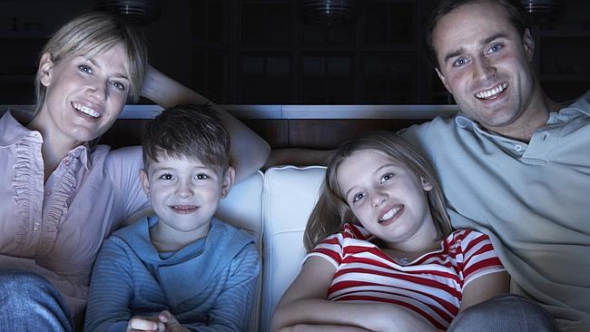  Young couple eating popcorn and watching TV together at home 