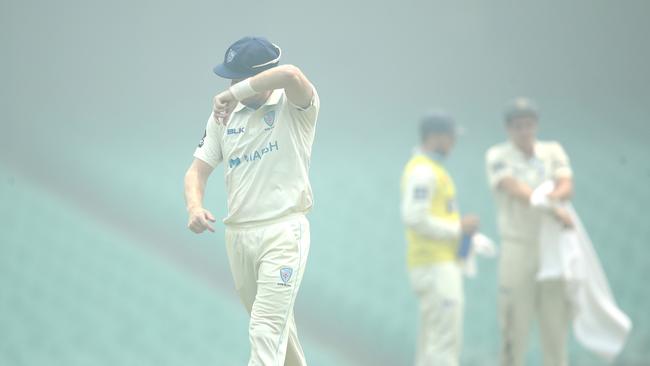 NSW players guard their eyes from smoke haze during a Sheffield Shield game. Picture: Phil Hillyard