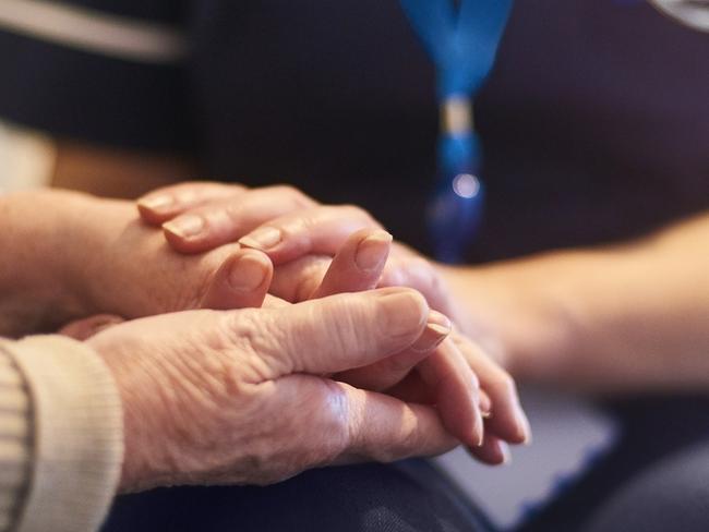 A female nurse consoles a senior patient at home, aged care generic