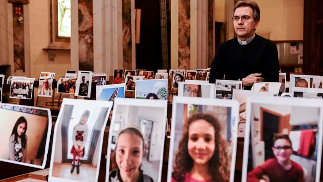 Don Giuseppe Corbari, parson of the Church of Robbiano, poses amidst photographs sent in by his congregation and glued to empty church pews in Giussano. Picture: AFP