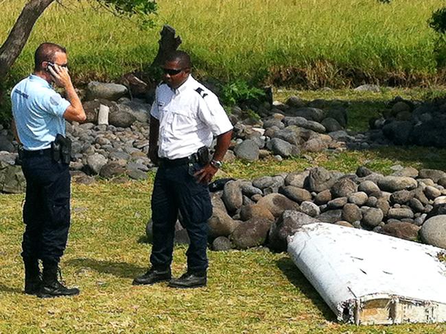 We found something ... A policeman and a gendarme stand next to a piece of debris from an unidentified aircraft found in the coastal area of Saint-Andre de la Reunion, in the east of the French Indian Ocean island of La Reunion. Picture: AFP