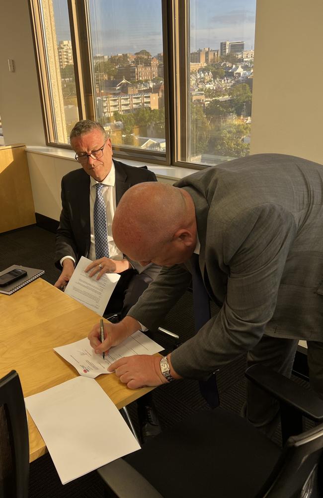 Transport Minister David Elliott signing the new rail agreement.