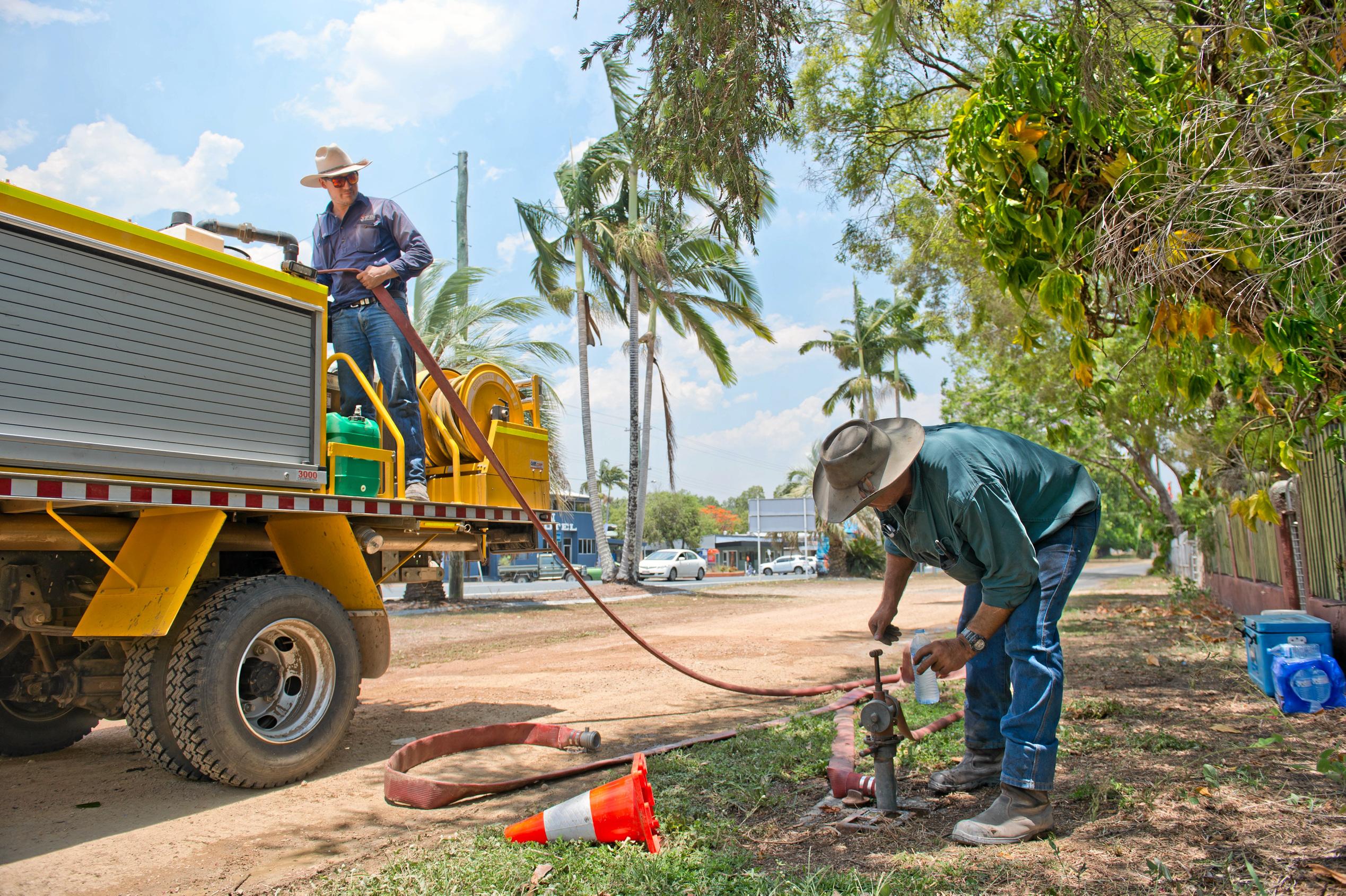 Lachlan and Chris Borg, a father and son from Marian, refill their fire truck before returning to help fight fires burning near Finch Hatton on Wednesday. Picture: Emma Murray