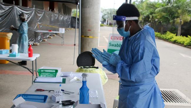 A health worker prepares to do tests for COVID-19 outside a makeshift clinic in a sports stadium in Port Moresby. Picture: AFP