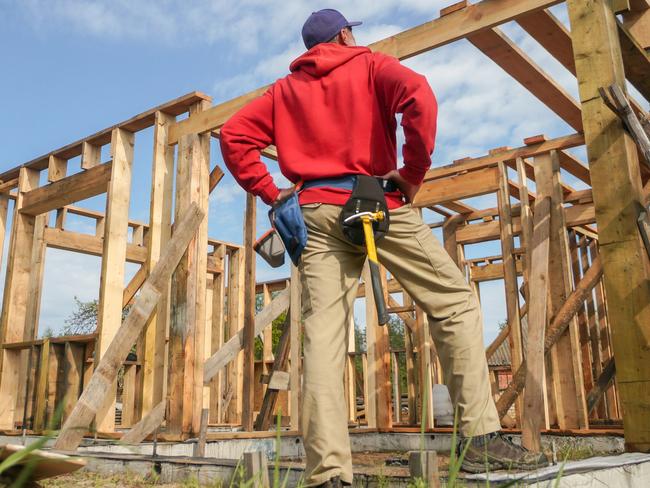 Developing Queensland - roofer, carpenter working on roof structure at construction site.