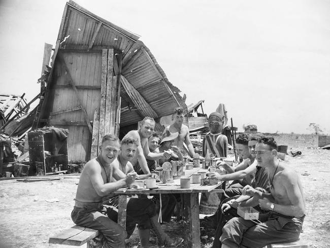 Troops of the 2/48TH Australian Infanctry Battalion lunch near the bombed-out Lutheran Mission Church in Sattelberg on November 29, 1943. The figure at the head of the table is a native carving of an angel. Picture: Courtesy Australian War Memorial 061235