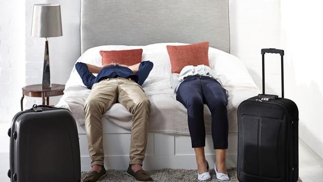 Indoor shot of mature couple lying on bed with luggage