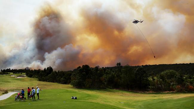 Golfers on the tee block at The Ridge Golf Course in Barden Ridge as water bombing helicopters refill their buckets. Picture: Toby Zerna