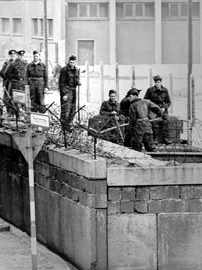 East German soldiers work on a second layer of the Berlin Wall at the allied Checkpoint Charlie crossing near the Friedrichstrasse in 1964.