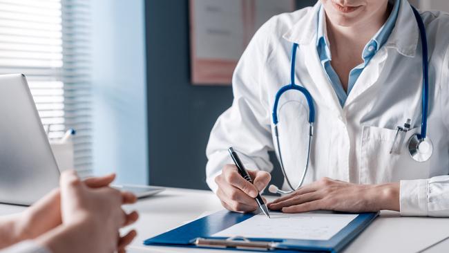 Doctor sitting at desk and writing a prescription for her patient