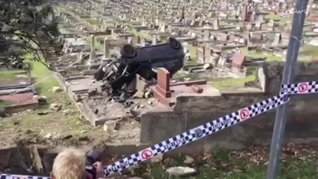 Car smashes through brick wall and crashes into tombstones