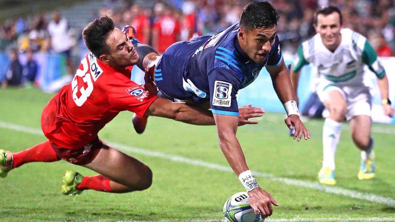 Rieko Ioane of the Blues touches down to score his third try despite the efforts of Phil Burleigh of the Sunwolves.