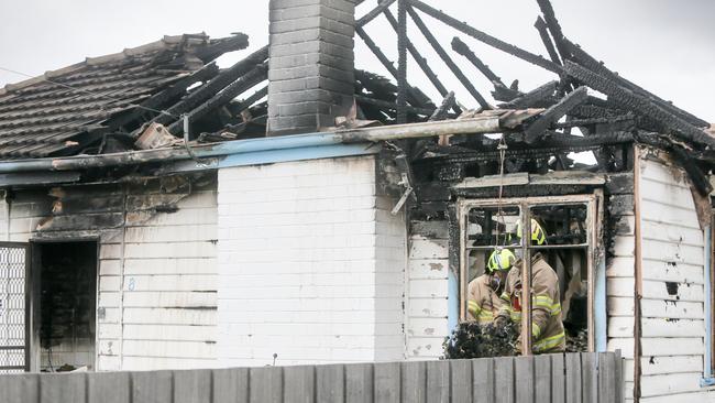 Firefighters shovel ash and coals out of a window at a house destroyed by fire at Mayfield, Launceston. Picture: PATRICK GEE