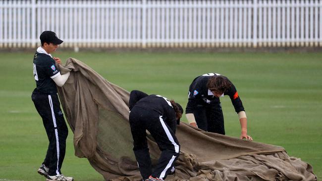 Wet weather marred many cricket games on the weekend. Western Suburbs players pull nn the hessian a passing shower delays play during Poidevin Gray Shield match on Sunday.