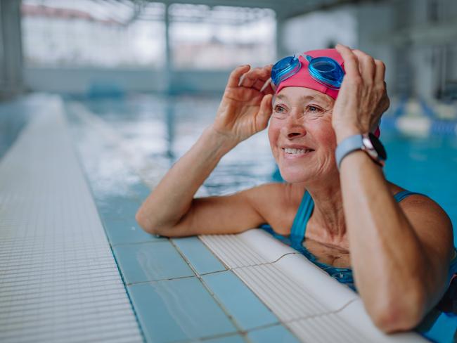 A happy senior woman in swimming pool, leaning on edge. Active retirement generic.