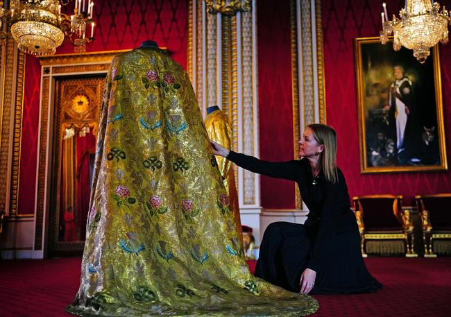 Caroline de Guitaut, deputy surveyor of the King's Works of Art for the Royal Collection Trust, adjusts the Imperial Mantle, which forms part of the Coronation Vestments, displayed in the Throne Room at Buckingham Palace in London, England. The vestments will be worn by King Charles III during his coronation at Westminster Abbey on Saturday. Picture: Getty Images