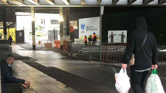 A shopper walks under Parramatta railway bridge after some essential grocery shopping.