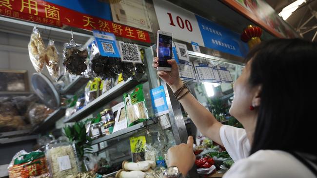 A woman scans an Alipay code to make a payment in Beijing. Picture: How Hwee Young/EPA/Shutterstock