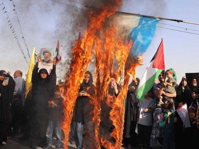 TOPSHOT - Iranians burn an Israeli flag during a rally in Tehran on October 2, 2024, a day after Iran fired a barrage of missiles at Israel. Israel vowed to make Iran "pay" for firing a barrage of missiles at its territory, with Tehran warning on October 2 that it would launch an even bigger attack if it is targeted. (Photo by ATTA KENARE / AFP)