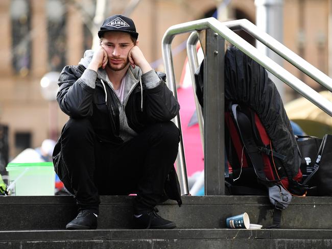 A resident of Tent City sits on steps next to his bags before leaving Martin Place.