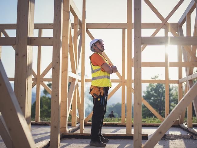 Shot of a senior builder working on wooden house in nature.